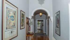 A hallway with wooden flooring, framed artwork on the walls, and a patterned rug. - Central, Classic, Contemporary , Comfortable, Convenient , Charming (Ballarat Central)