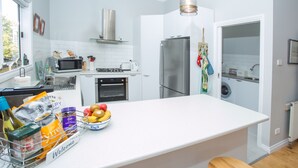 A modern kitchen with white cabinets, stainless steel appliances, and a central island with a fruit bowl. - Central, Classic, Contemporary , Comfortable, Convenient , Charming (Ballarat Central)