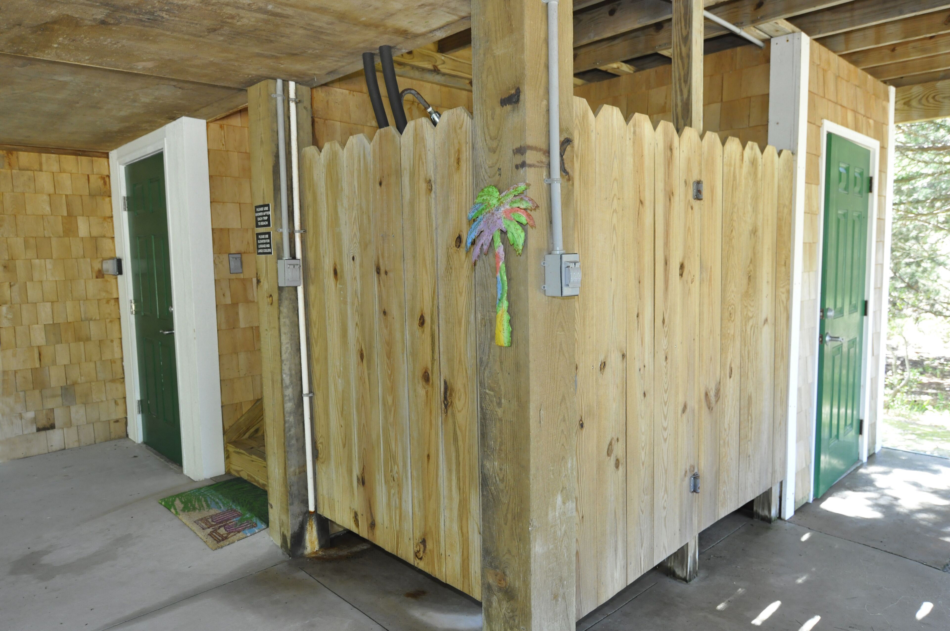 A wooden structure with a green door, a white door, and a wooden fence.