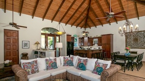 A spacious living area with a large woven sectional sofa, a glass coffee table, and a ceiling fan. - La Bella Vita: Full AC! Pool! Sunset Views All Year! (St. John)