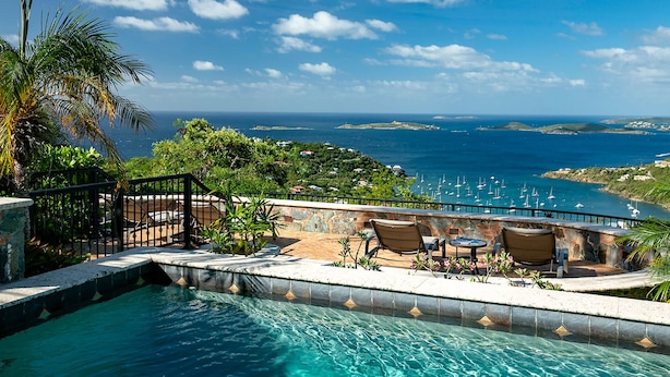 A pool with a view of the ocean and boats, surrounded by palm trees and outdoor furniture. - La Bella Vita: Full AC! Pool! Sunset Views All Year! (St. John)