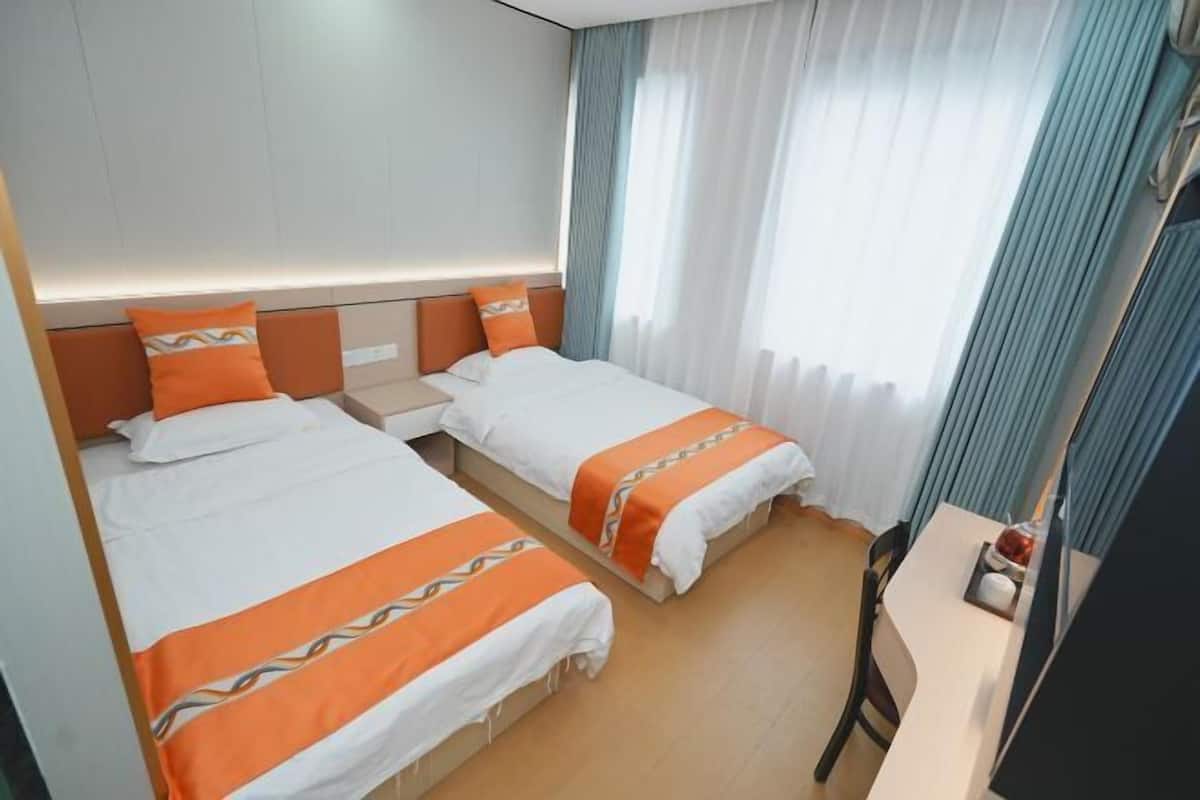 Une chambre d’hôtel avec deux lits, un bureau et une chaise.