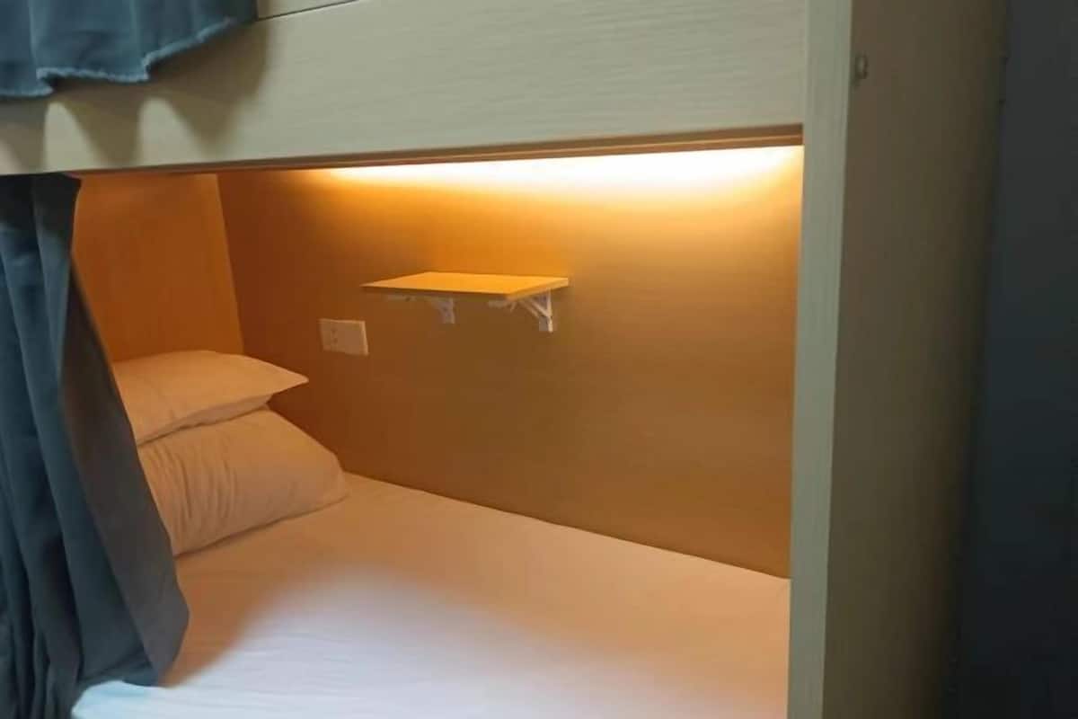 Un lit simple avec une tête de lit, une table de chevet et une étagère fixée au mur.