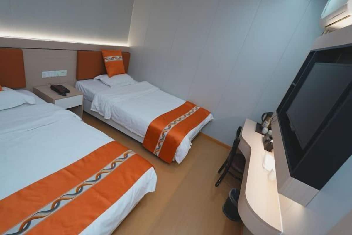 Une chambre d’hôtel avec deux lits, une télévision et une table de chevet.