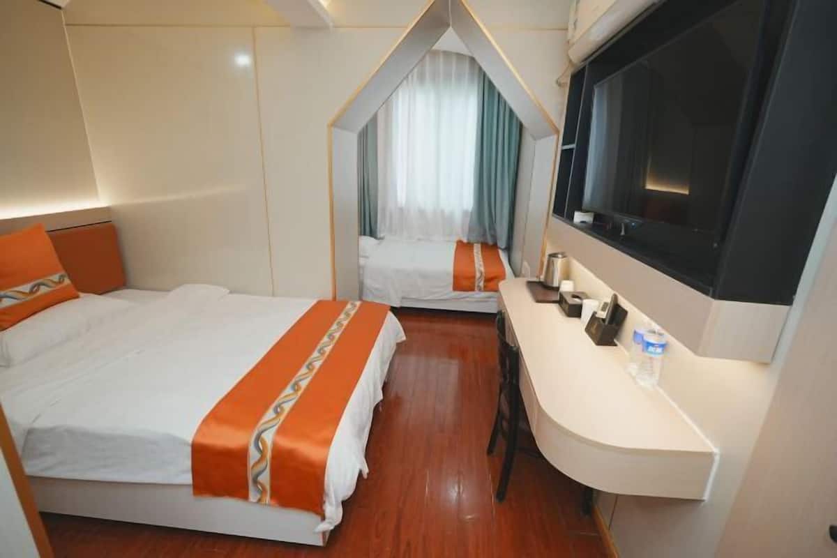 Une chambre d’hôtel avec deux lits, un bureau, une télévision et une fenêtre avec des rideaux.