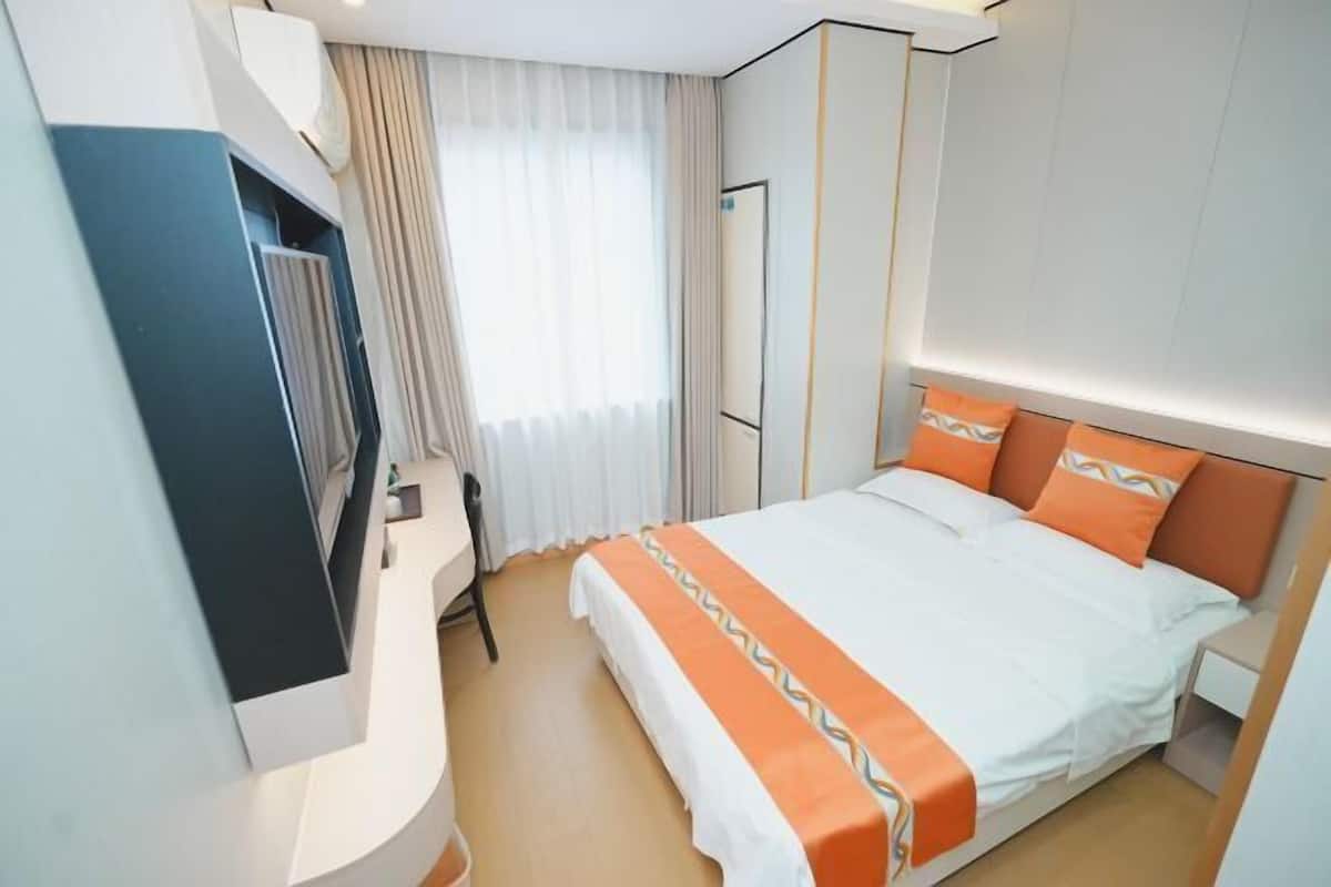 Une chambre d’hôtel avec un lit, une télévision, un bureau et une fenêtre avec des rideaux.
