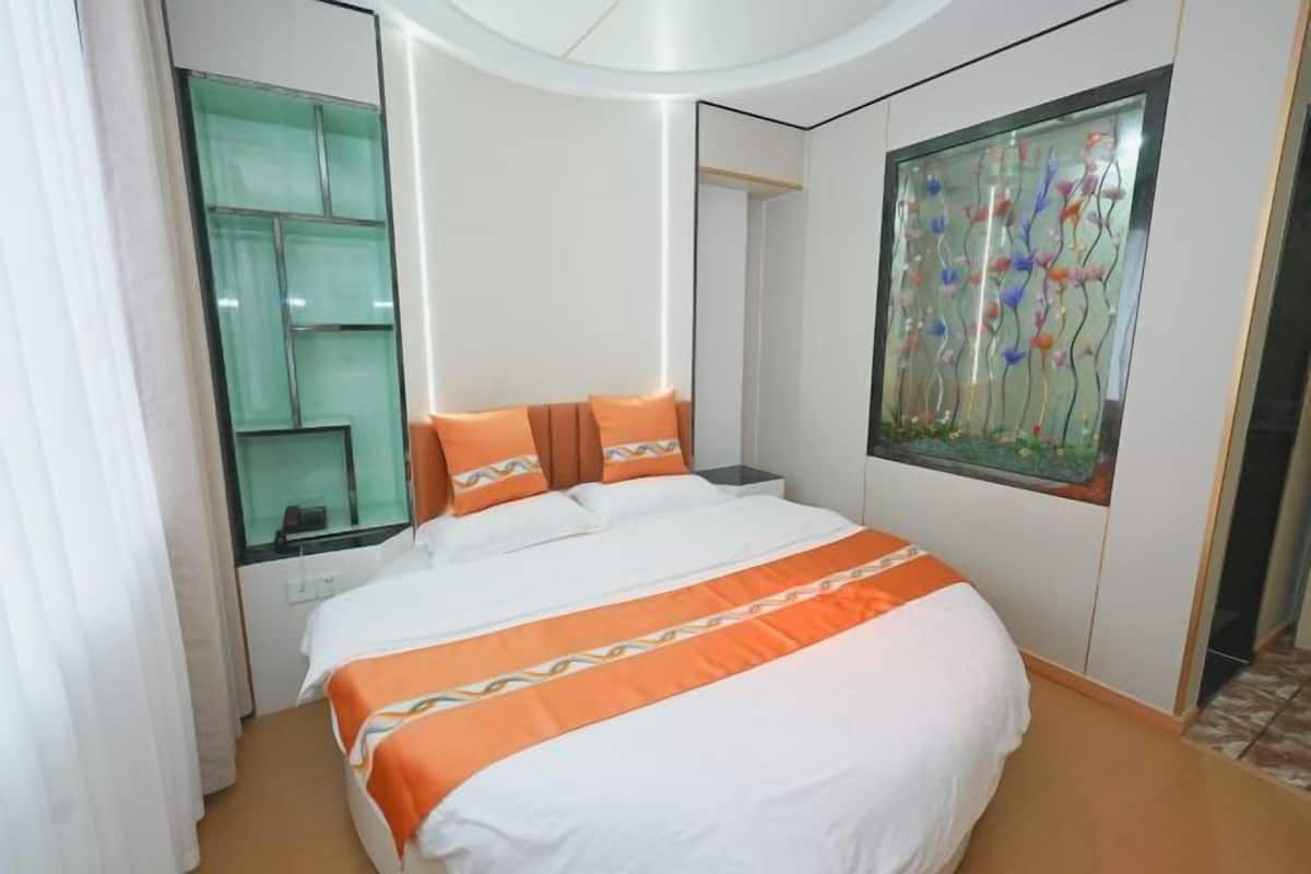 Une chambre d’hôtel avec un lit, une grande fenêtre et un élément décoratif en verre accroché au mur.