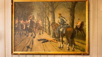 Una pintura de una escena de batalla histórica con soldados a caballo, montada sobre una plataforma de madera.