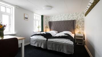 A bedroom with a bed, a desk, a chair, and a window.
