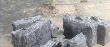 A pile of large, dark-colored, rectangular objects on a paved surface.