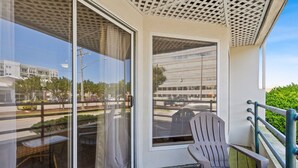 Un balcón con vistas a un edificio moderno, una silla y una mesa.