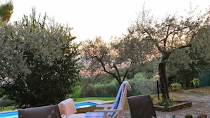 Un espace extérieur aménagé avec des fauteuils confortables, une table décorée de bougies et un arrangement floral.