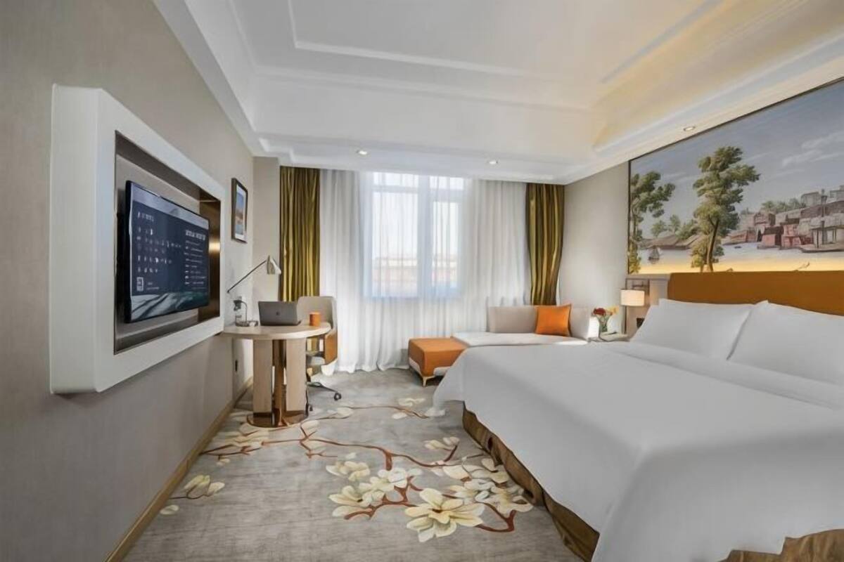 Ein Hotelzimmer mit Bett, Schreibtisch, Fernseher und einem Bild an der Wand.