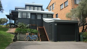 Een modern huis met twee verdiepingen, een garage, een fiets en een trap naar de bovenverdieping.