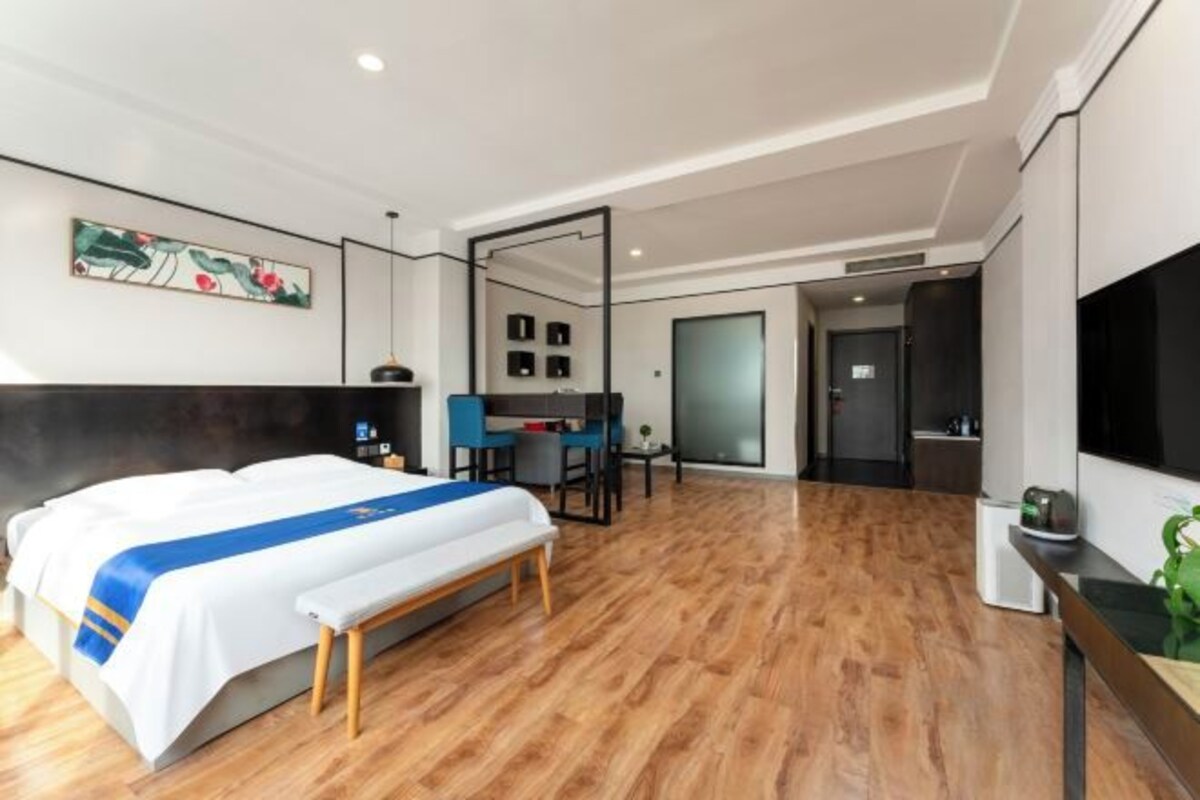 A modern hotel room with a large bed, a desk, and a seating area.