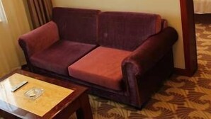 Ein Hotelzimmer mit einem roten Sofa, einem Holztisch und einem gemusterten Teppich.
