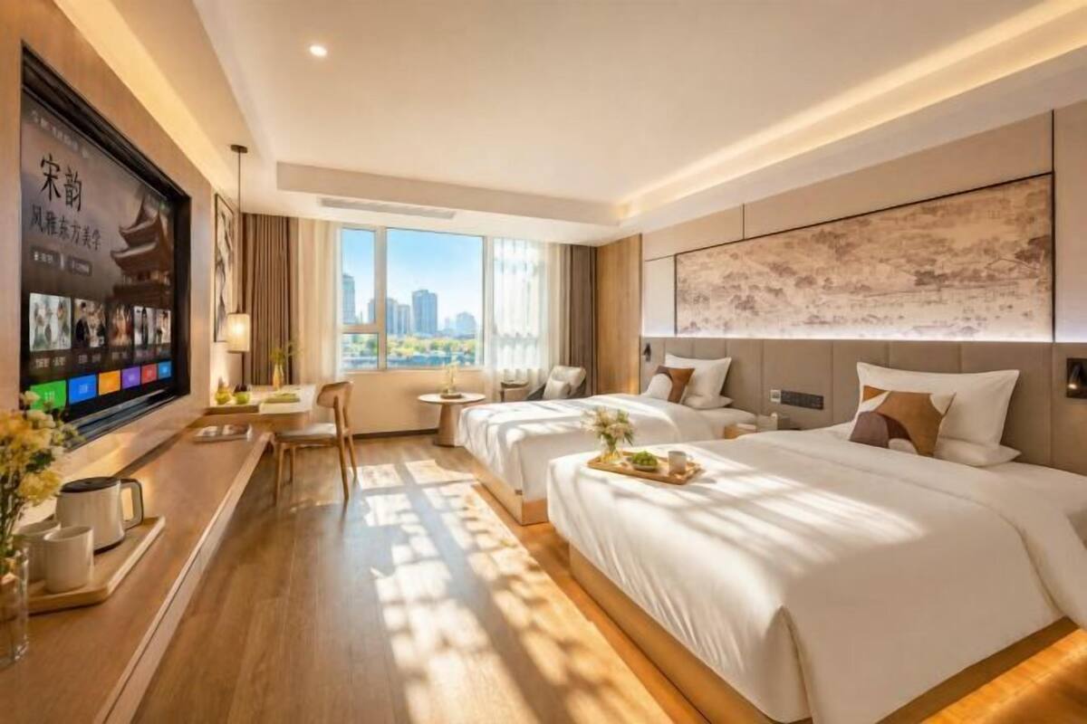 Une chambre d’hôtel avec un grand lit, un bureau, une chaise, une télévision et une vue sur la ville.