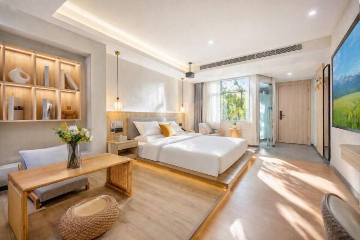 Une chambre moderne avec un grand lit, des tables de chevet, un bureau et une étagère fixée au mur.