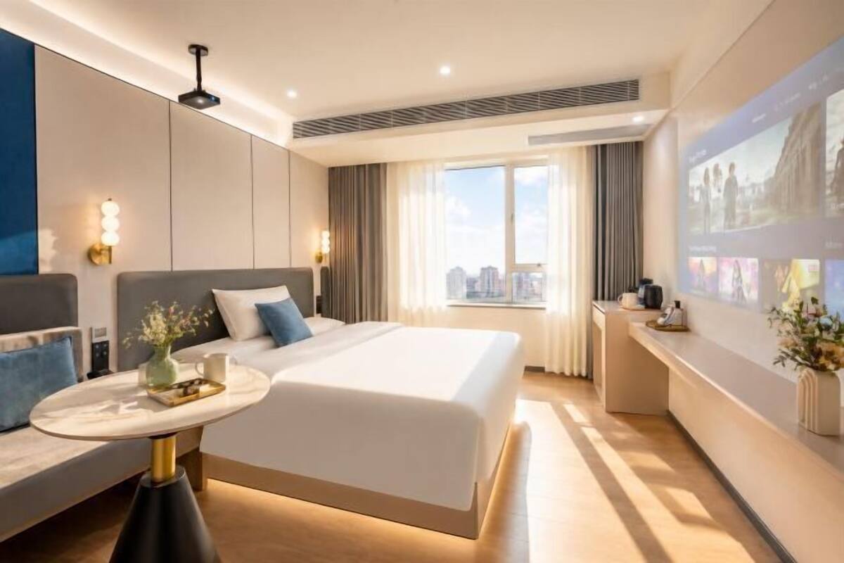 Une chambre d’hôtel moderne avec un lit, une table de chevet et une vue sur la ville.