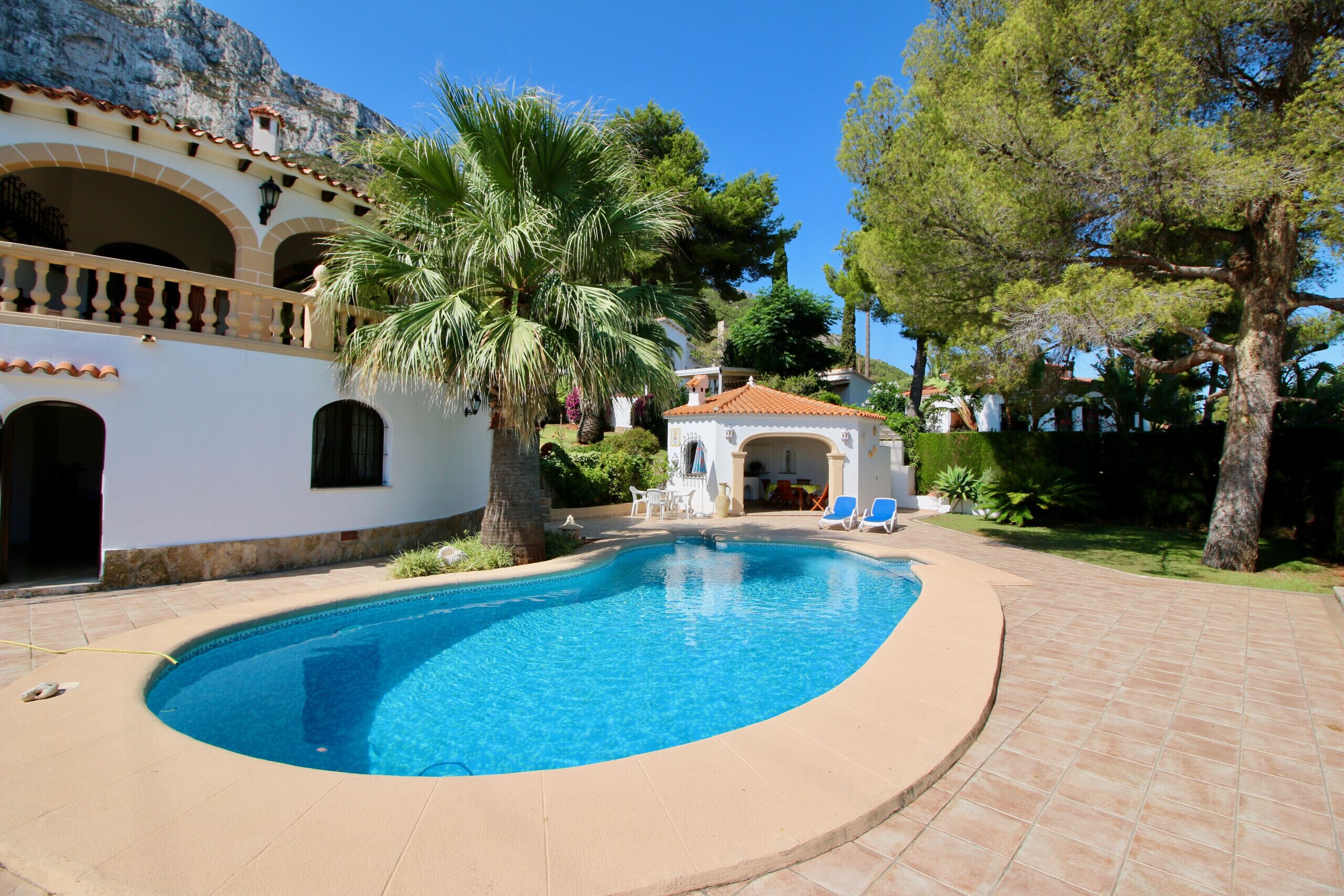 A swimming pool with a curved edge, surrounded by a tiled deck.