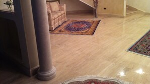 A spacious lobby with a beige carpet, a patterned rug, a sofa, and a tall column.