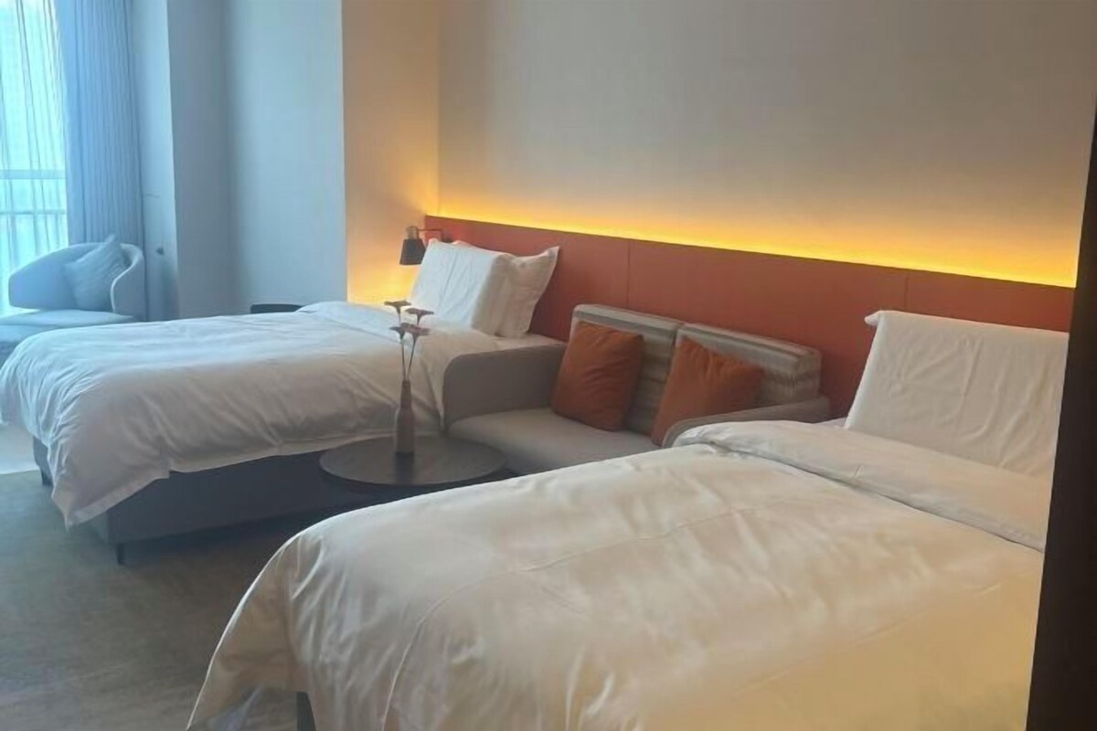 A hotel room with two beds, a sofa, and a small table.