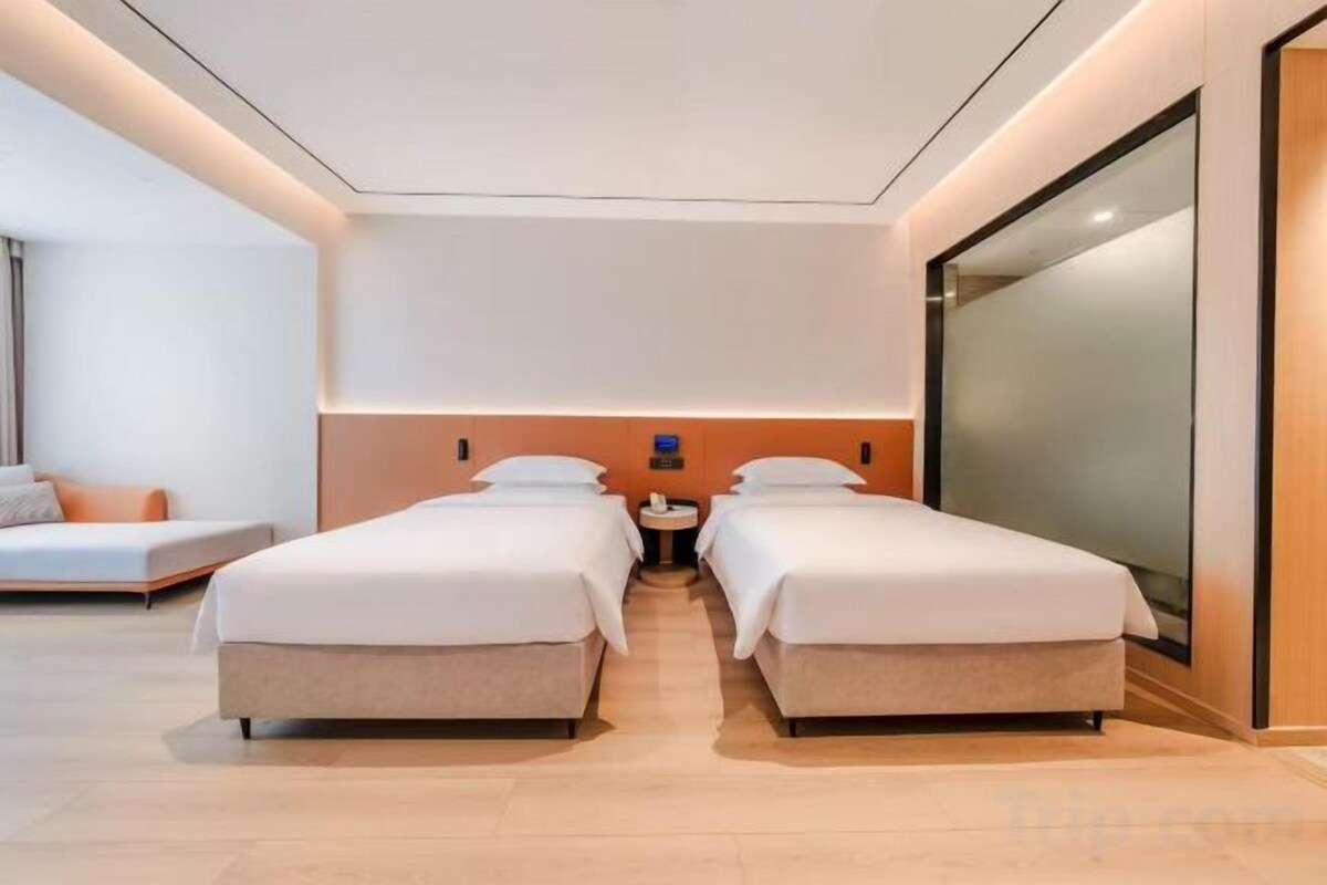 A hotel room with two beds, a sofa, and a large window.