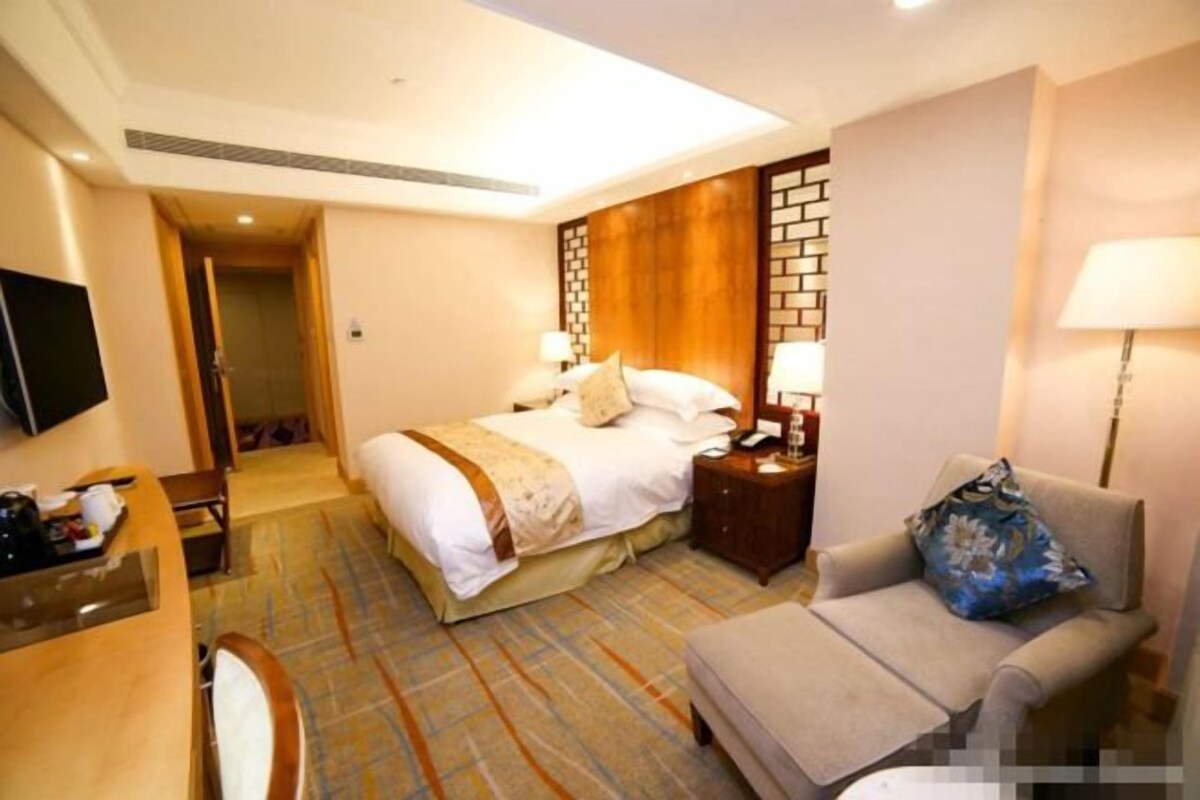 A hotel room with a bed, a sofa, a desk, and a TV.