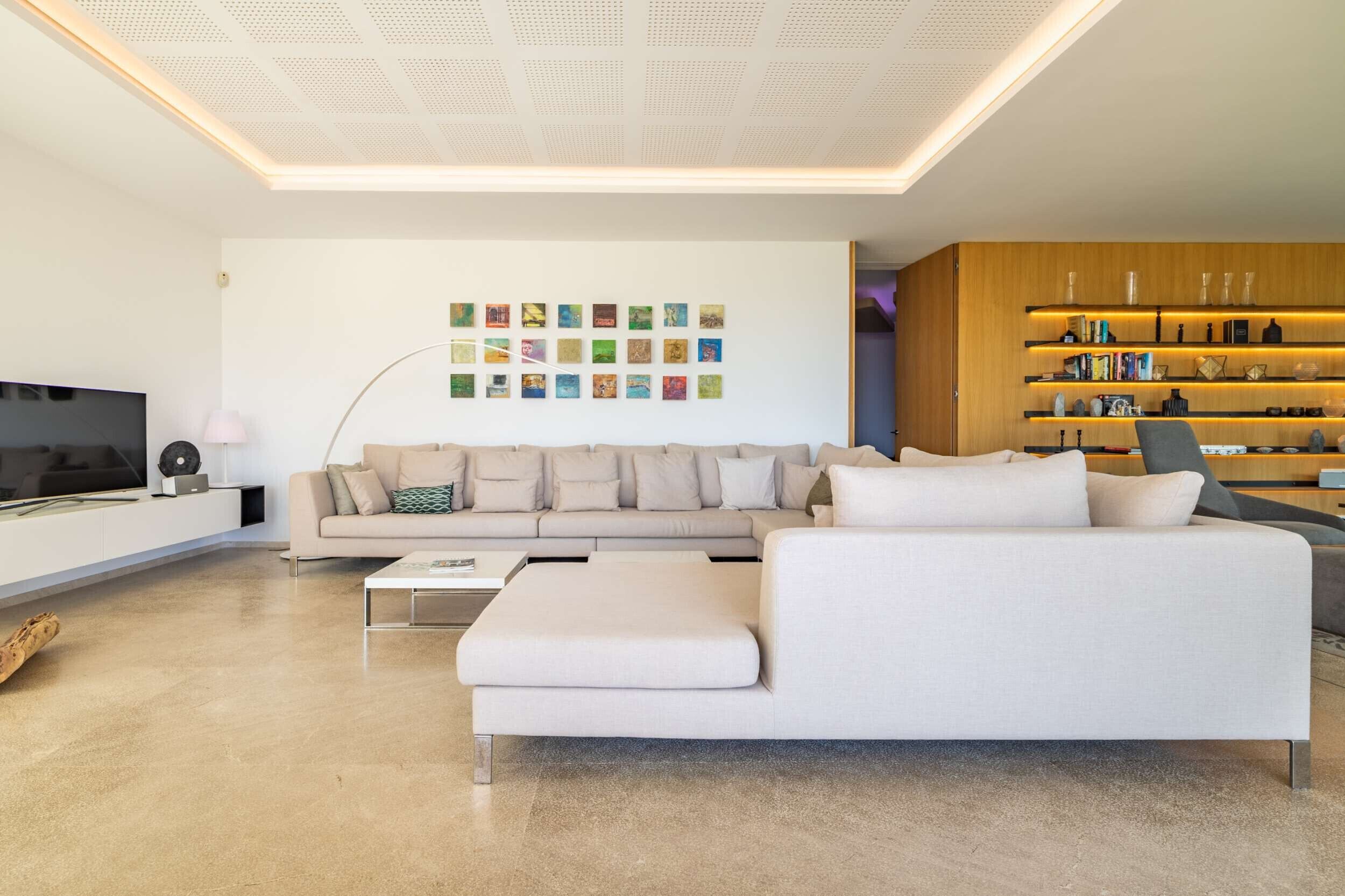 A modern living room with a sofa, coffee table, and a wall with framed artwork.