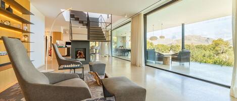 A modern living room with a fireplace, comfortable seating, and a staircase leading to an upper level.