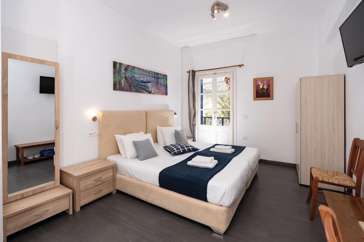 A bedroom with a bed, bedside tables, a wardrobe, a mirror, and a television.