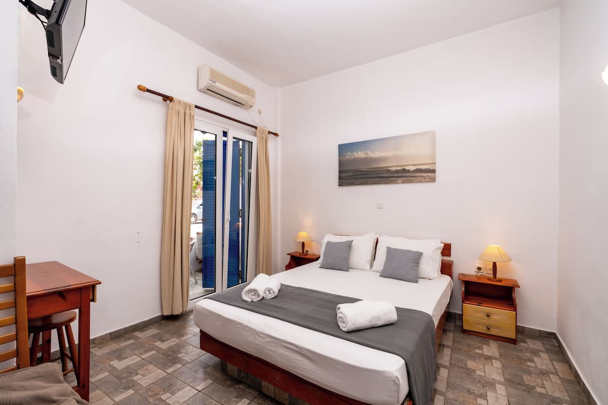 A hotel room with a bed, bedside tables, a desk, and a chair.