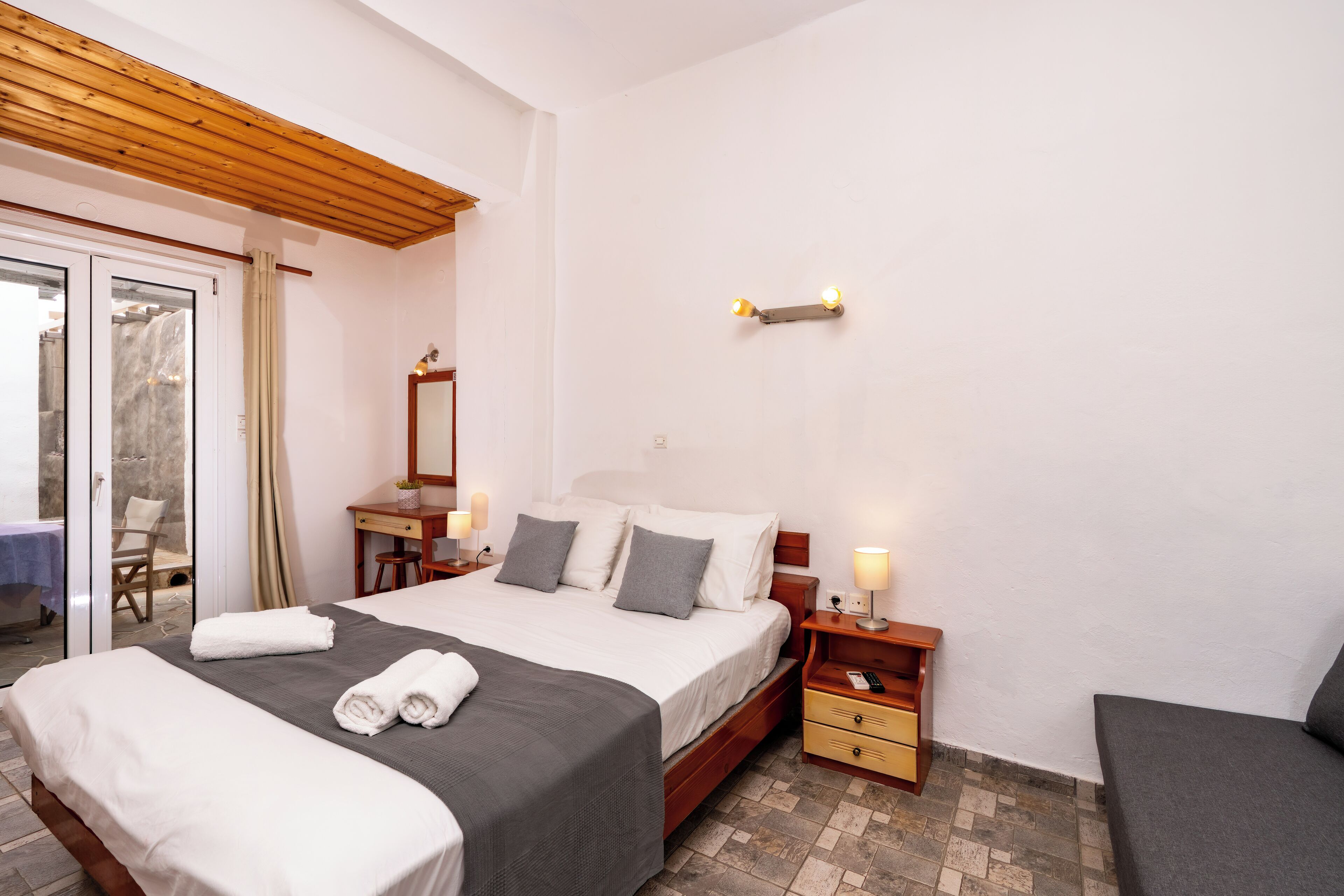 A hotel room with a bed, bedside tables, a desk, and a chair.