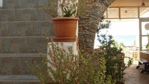 Una escalera con macetas de terracota con plantas, que conduce a un arco de piedra.