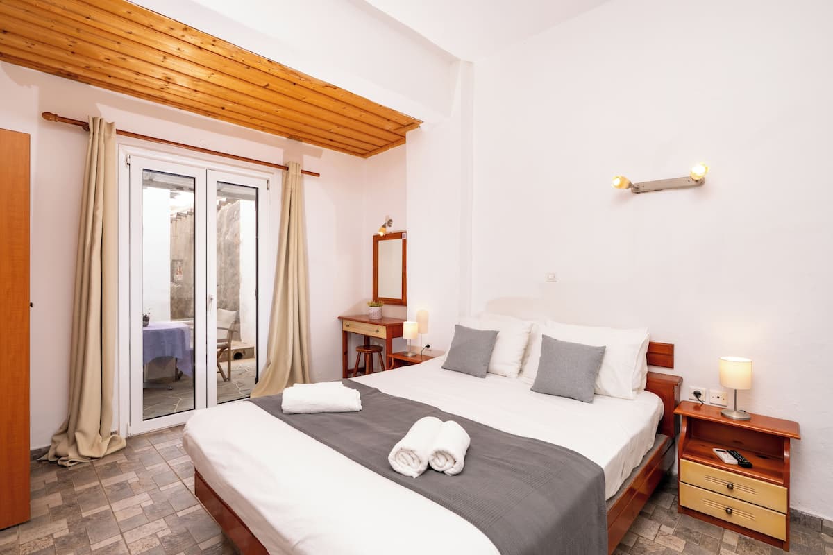 A hotel room with a bed, bedside tables, a desk, and a mirror.