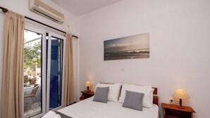 Habitación de hotel con cama, un cuadro, una ventana con cortinas y vistas al exterior.