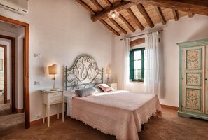 Un dormitorio con cama, mesitas de noche, un armario y una ventana con cortinas.
