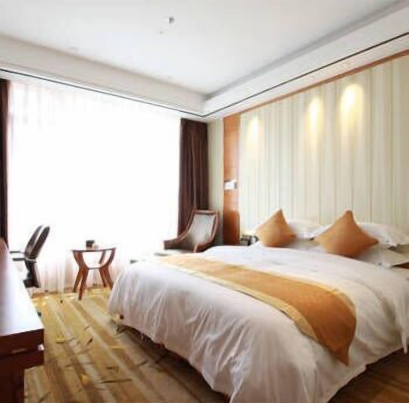A hotel room with a large bed, a desk, and a chair.