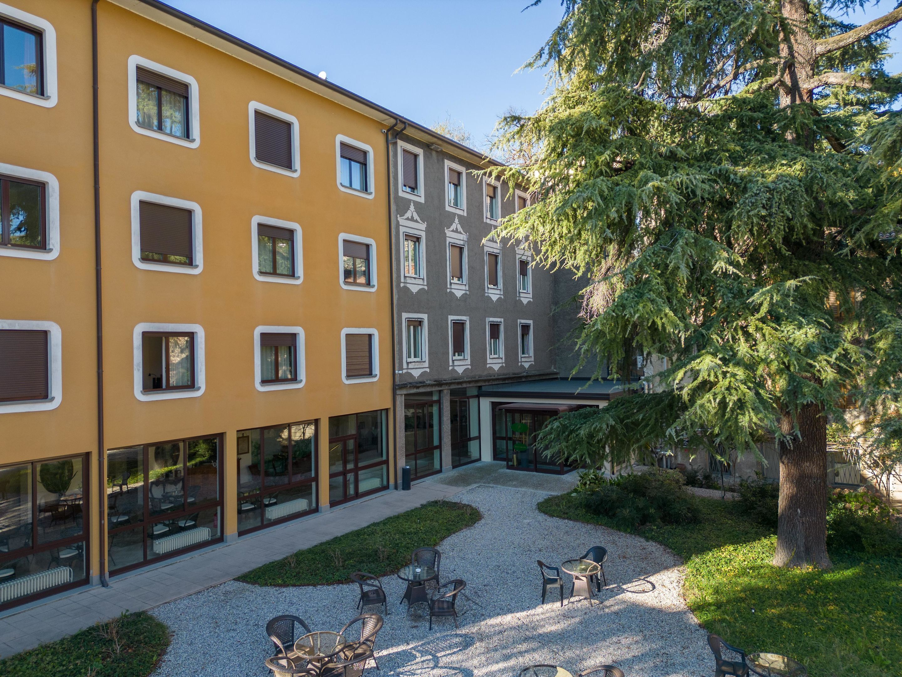 A courtyard with outdoor seating, a building with multiple windows, and a tree.