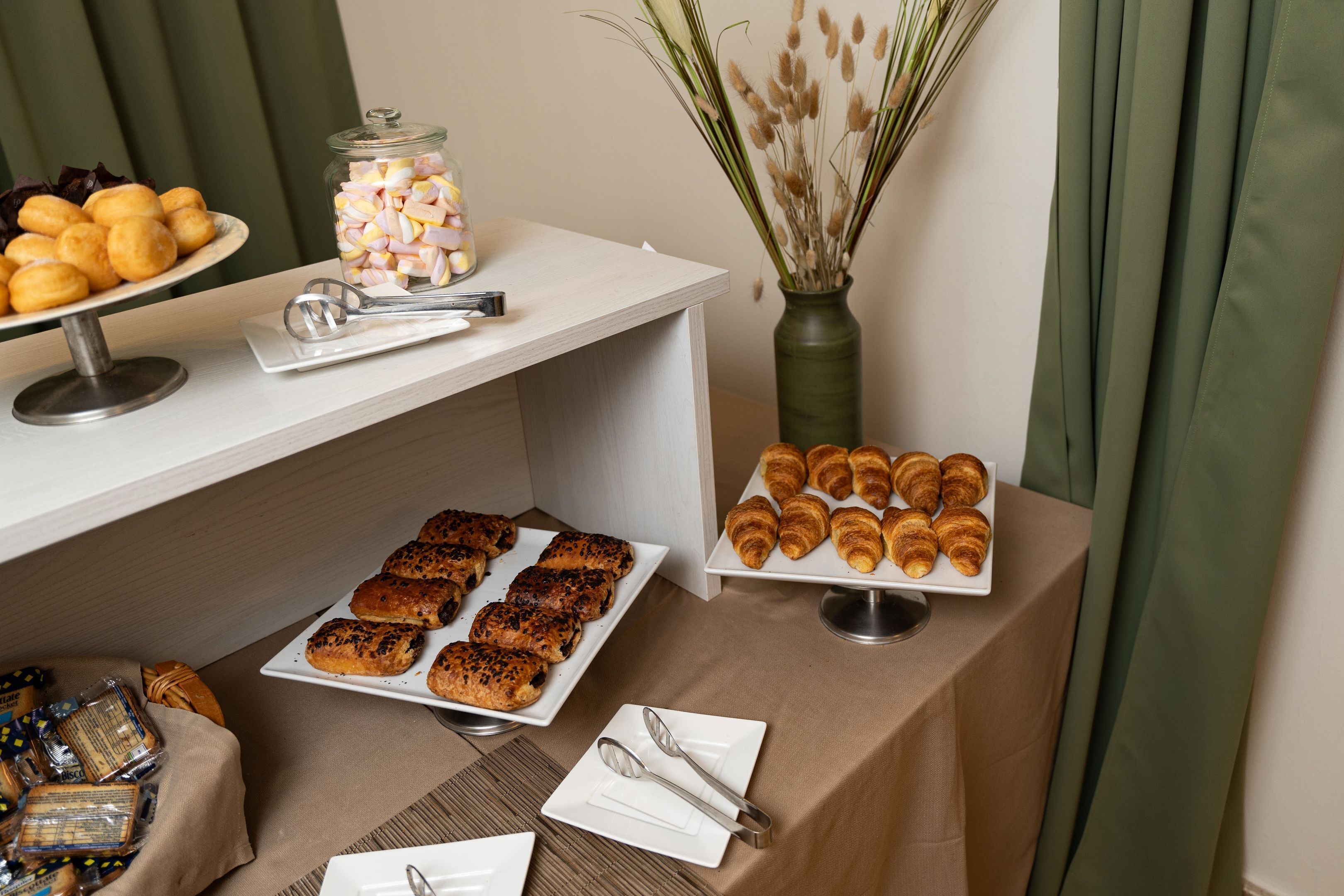 Een buffet met gebak, een pot met snoepgoed en een vaas met gedroogde planten.
