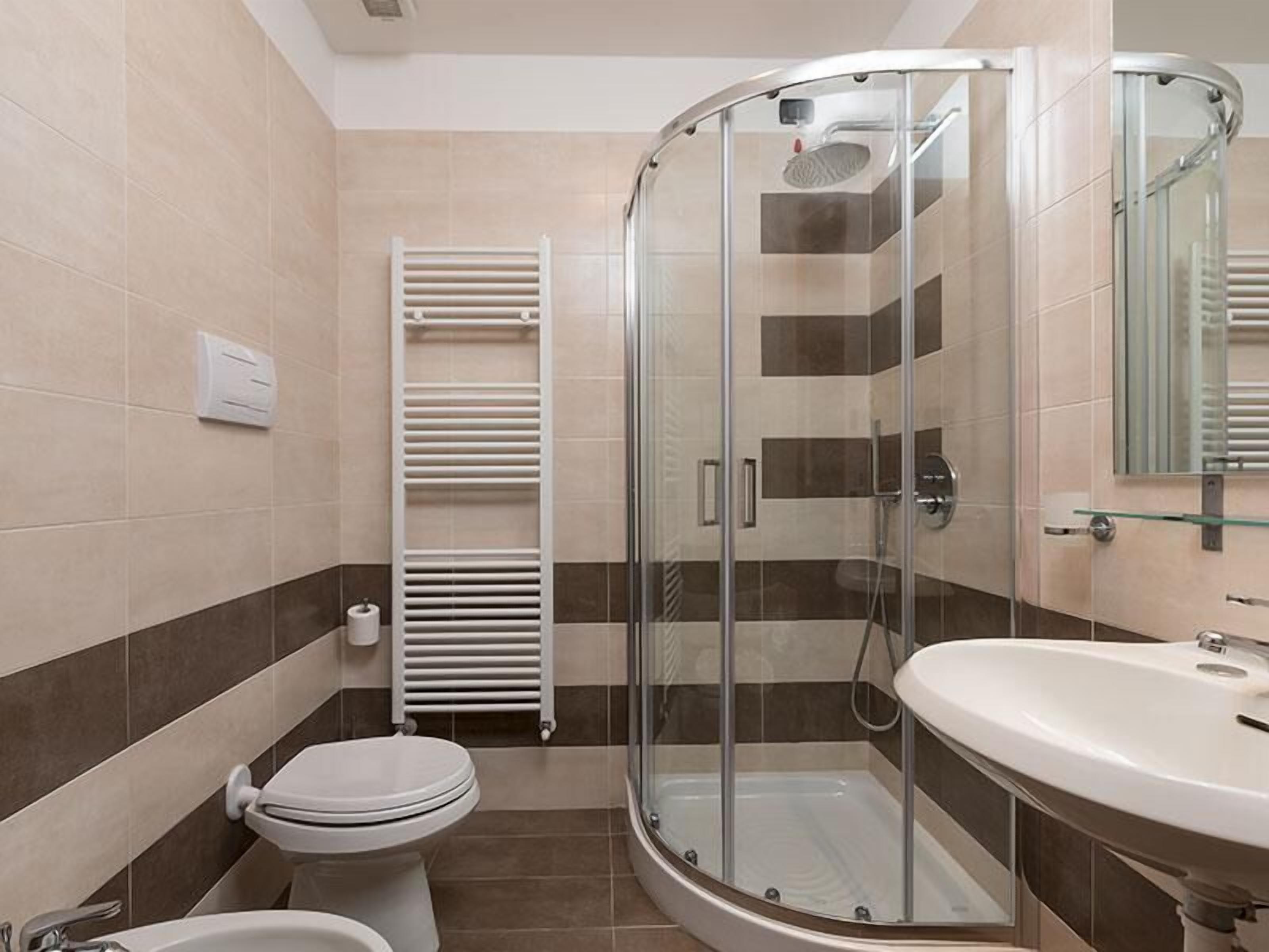 A modern bathroom with a glass-enclosed shower, a toilet, and a sink.