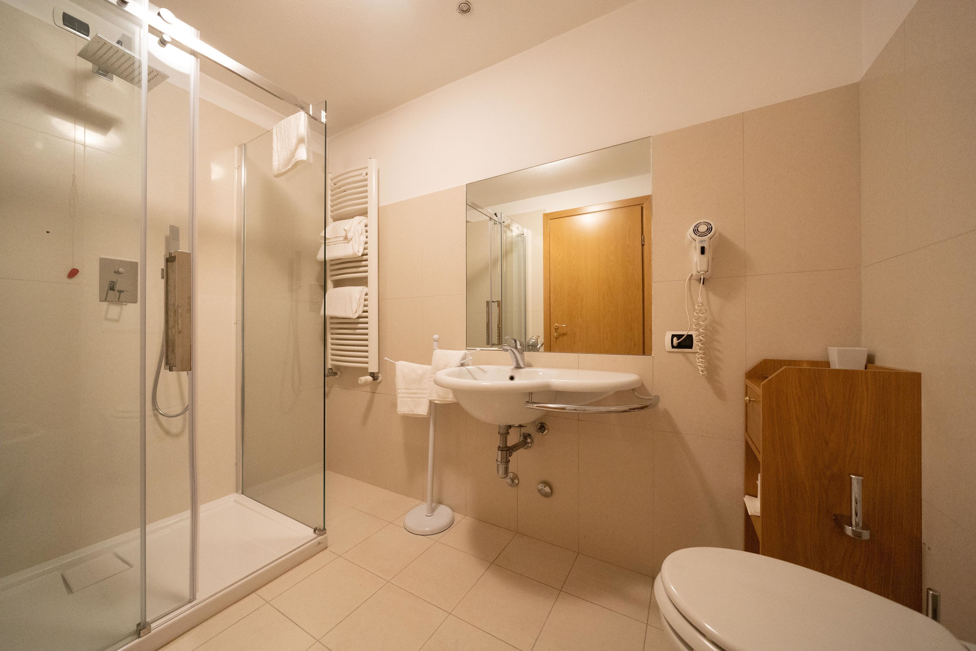 A modern bathroom with a glass shower enclosure, a sink with a mirror above it, and a wooden cabinet.