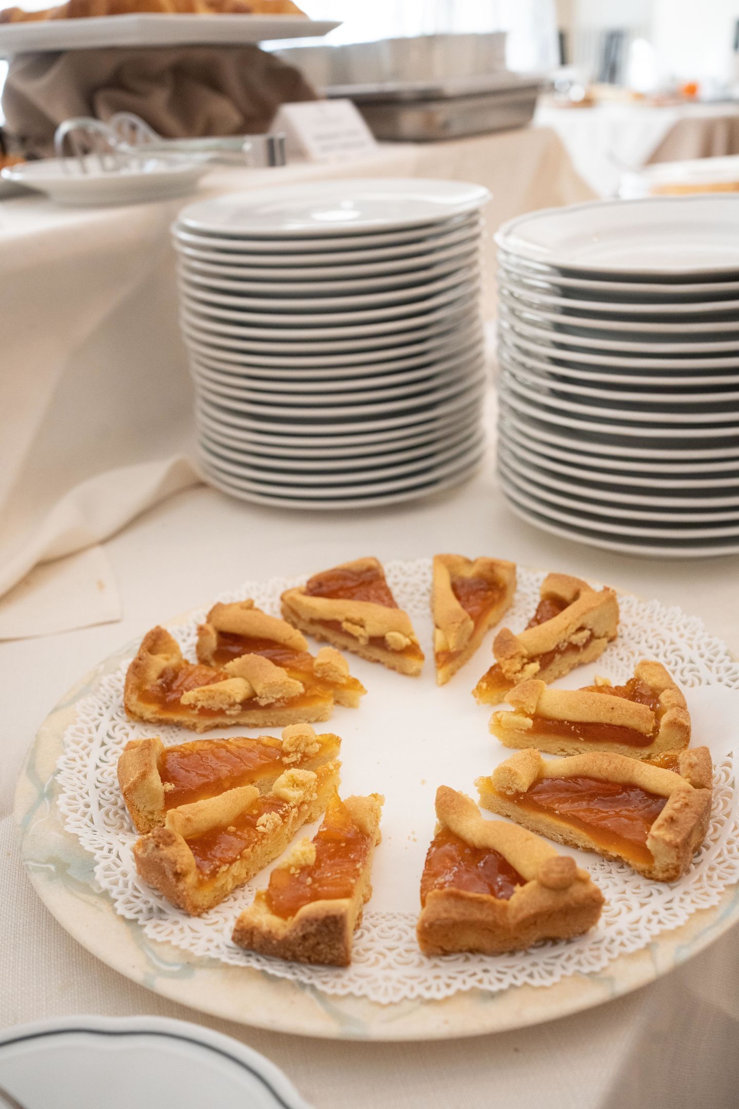 A table with stacks of plates and a plate of sliced pie.