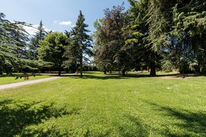A park with a well-maintained lawn, several trees, and a clear sky. - Hotel San Pancrazio (Trescore Balneario)