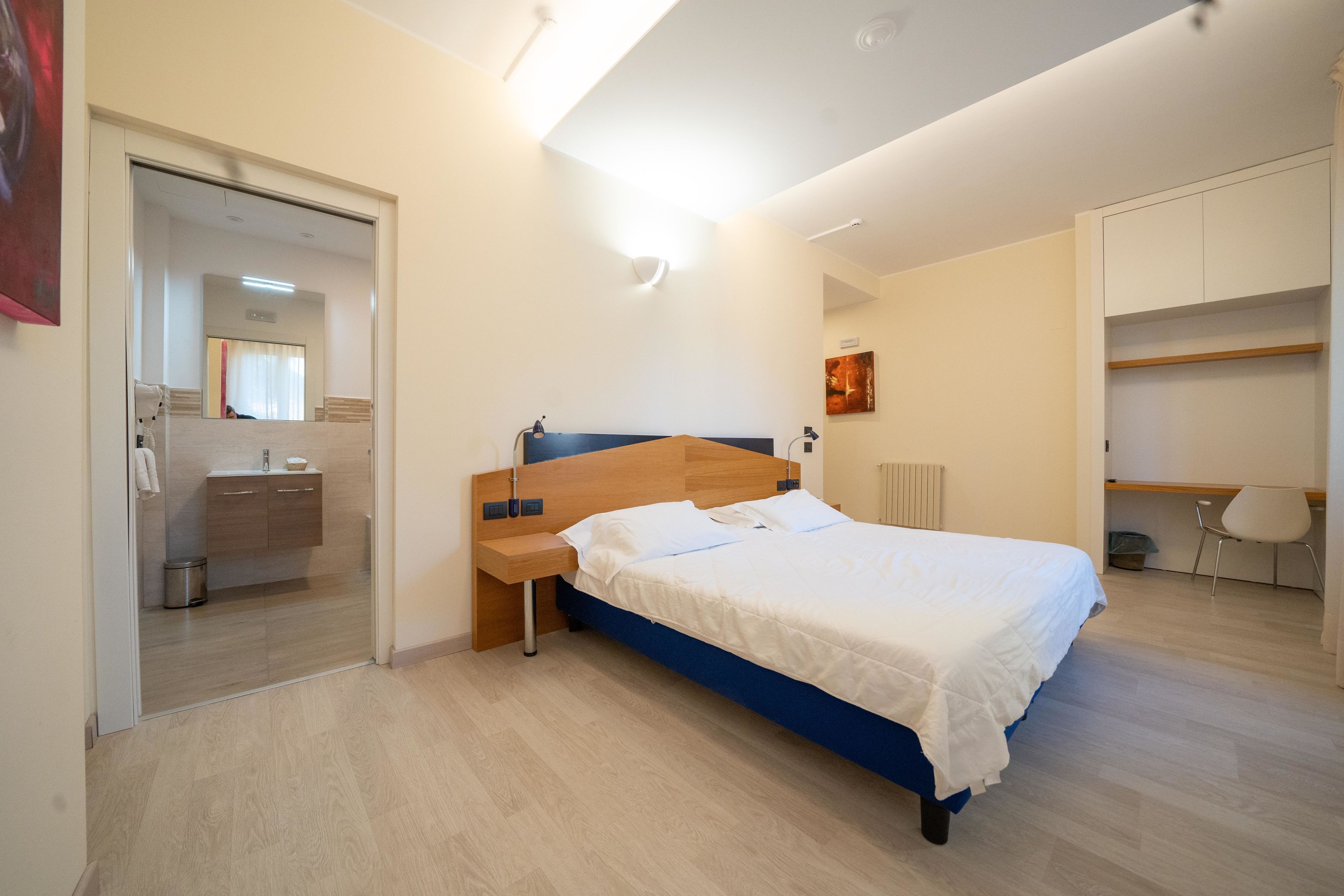 Une chambre moderne avec un lit, une table de chevet et un espace bureau.