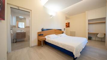 Une chambre moderne avec un lit, une table de chevet et un espace bureau.
