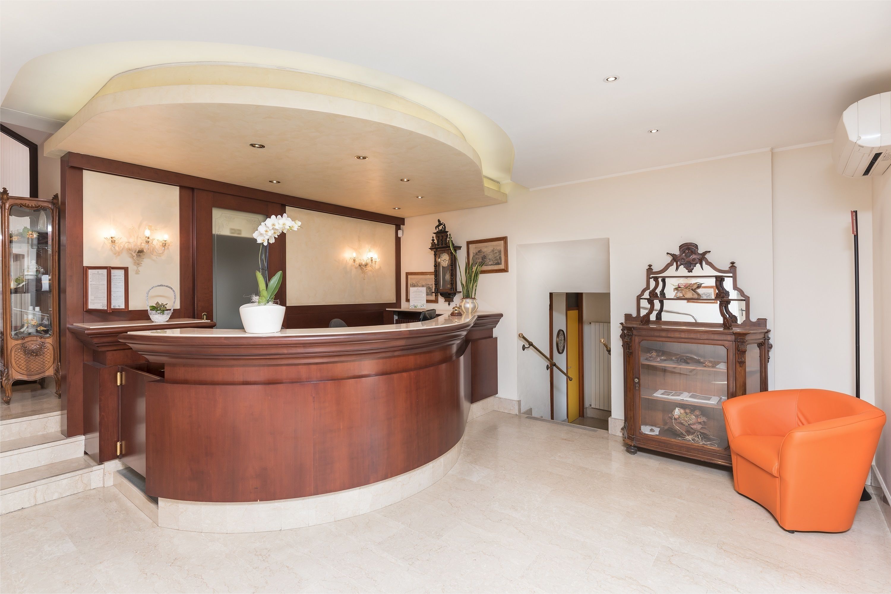 A reception area with a wooden reception desk, a potted orchid, and a vintage clock.