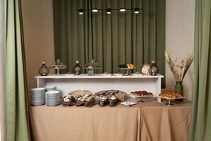 A buffet setup with various food items and serving dishes, arranged on a table with a beige tablecloth. - Hotel San Pancrazio (Trescore Balneario)