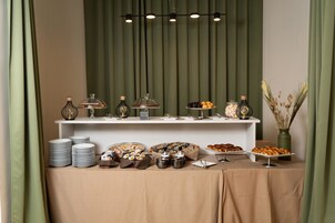 Un'impostazione a buffet con diversi cibi e stoviglie, disposti su un tavolo ricoperto da una tovaglia beige.