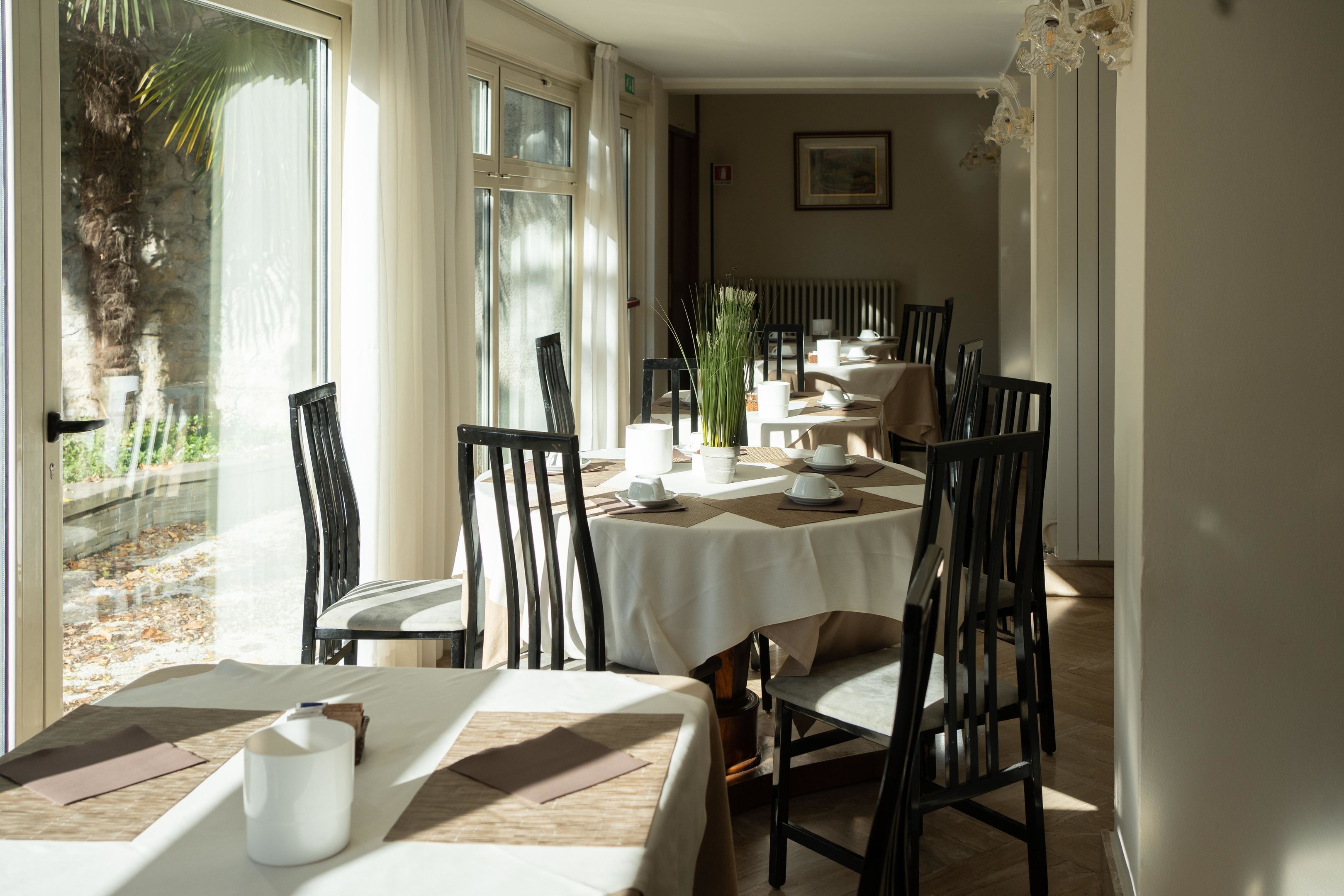 A dining area with tables set for four, chairs, and a view of a palm tree outside.